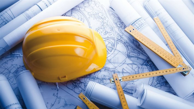 Būvnieka ķivere nolikta uz rasējumiem