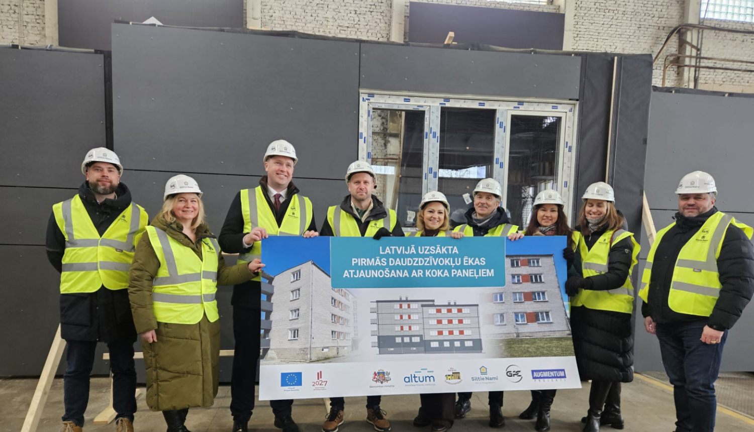 Ekonomikas ministrs un citi iesaistītie tur informatīvu plakātu par koka paneļu ražošanas uzsākšanu