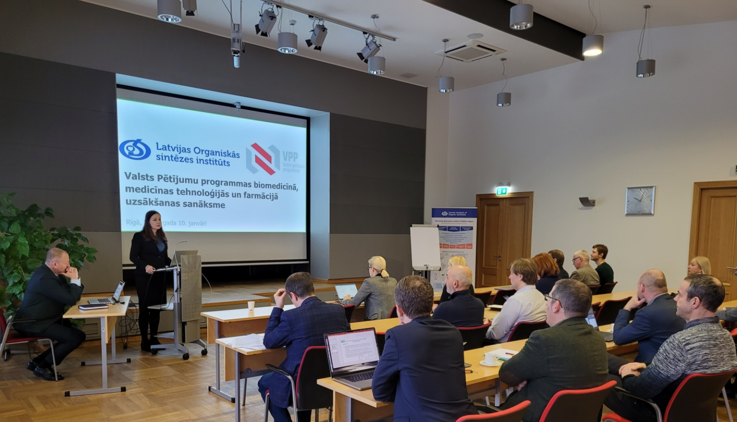 Sieviete prezentē, auditorija skatās prezentāciju